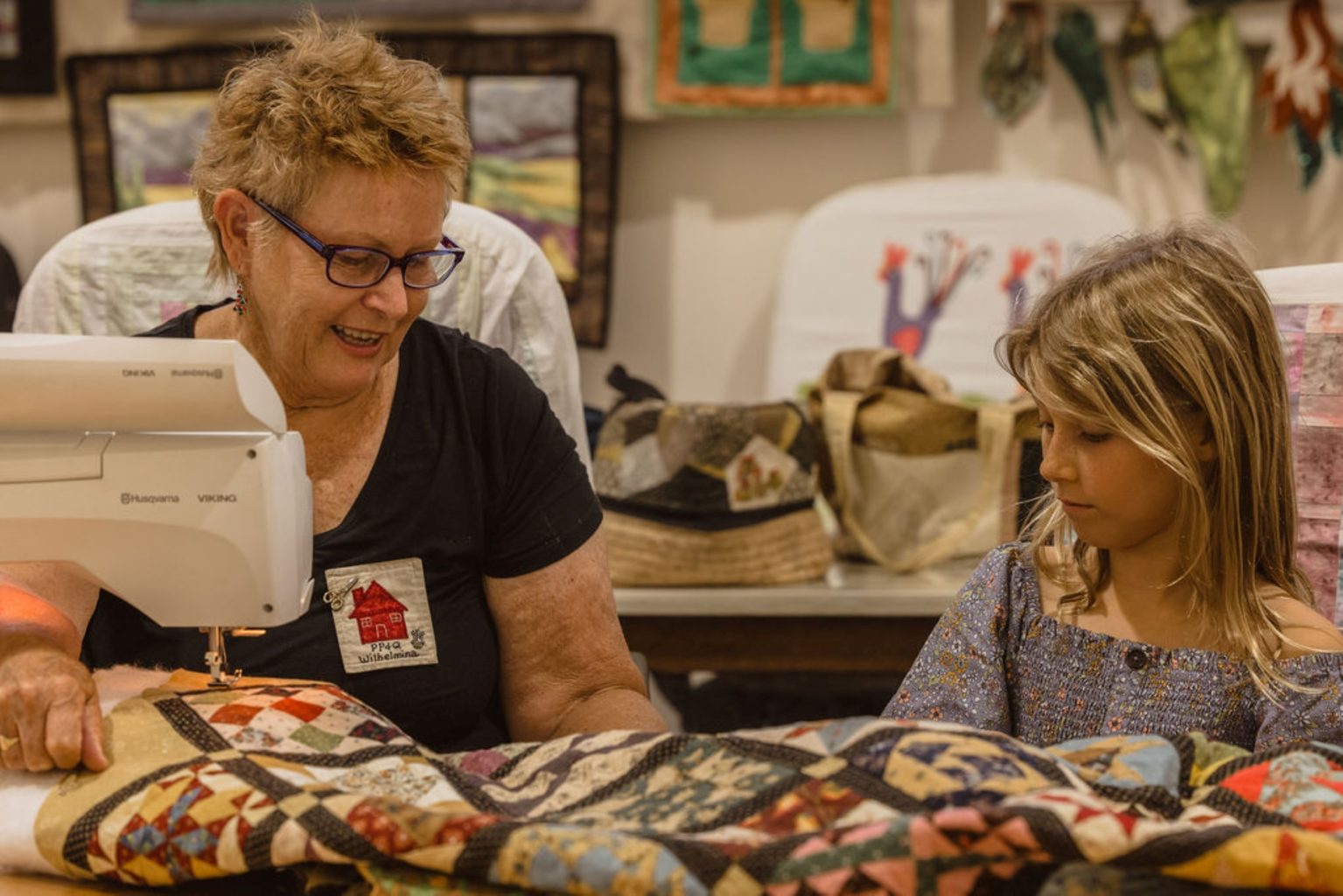 Older woman showing young girl a quit on a sewing machine.